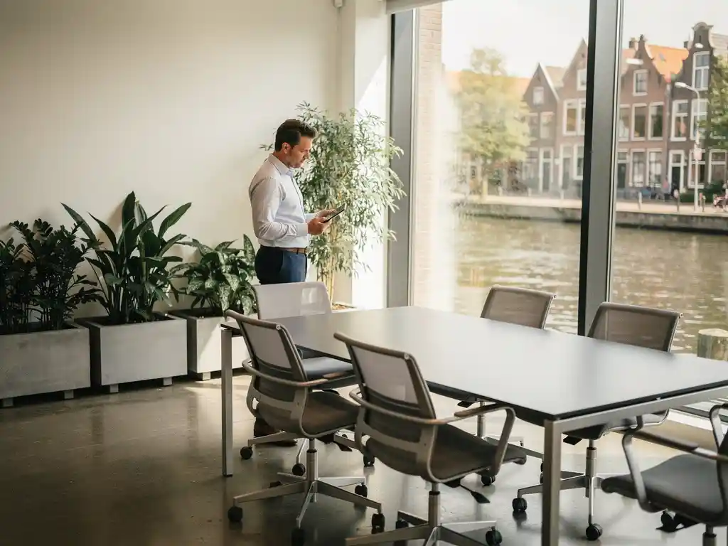 Professional inspecteert modern kantoor in Utrecht met vloer-tot-plafond ramen, kanaluitzicht en ergonomisch meubilair.