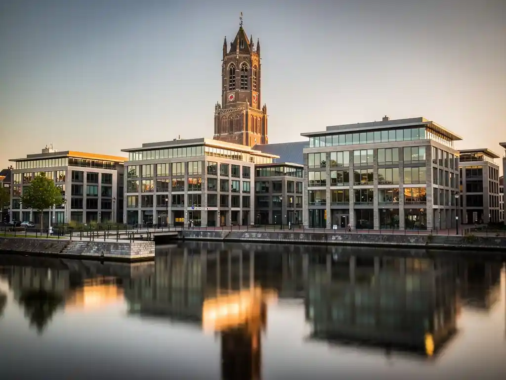Utrechts Dom Tower boven moderne glazen kantoorgebouwen langs een rustig kanaal in warm middaglicht.